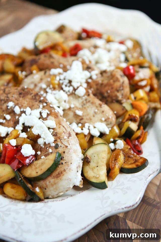 Close-up shot of a serving of Skillet Balsamic Chicken with Sweet Peppers and Zucchini, beautifully glazed with balsamic vinegar and generously topped with crumbled feta cheese.