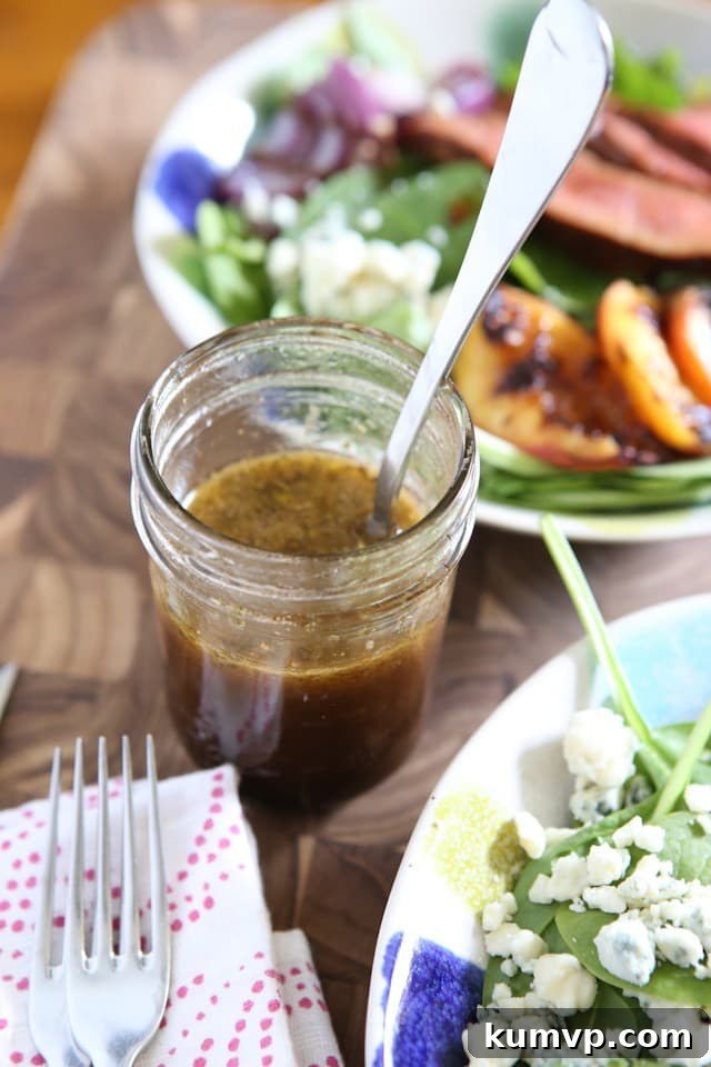 A charming jelly jar filled with vibrant honey balsamic dressing, with a fresh green salad blurred in the background, signaling health and homemade goodness.